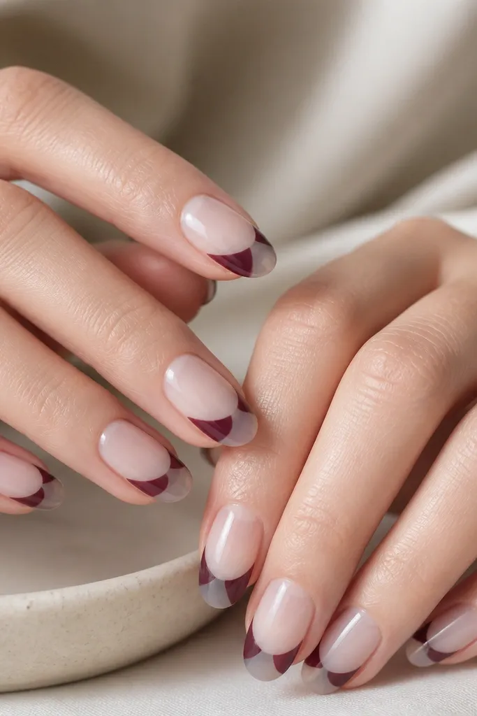 Short almond nails with a frosted clear negative space across the tip area. The French line is plum, but the center of the tip shows clear frosted jelly, creating a split look. Glossy top coat on the plum edges.