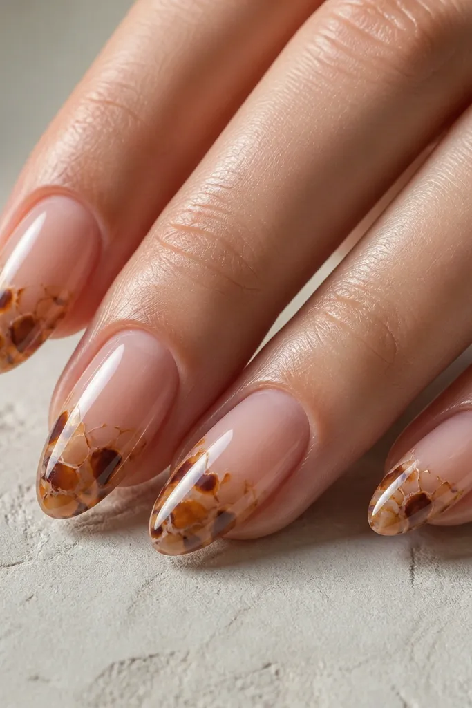 Nails with a sheer pink base and tortoise cracks in honey caramel and chocolate. The overall look is lighter and fresher, with a mirror-like shine.