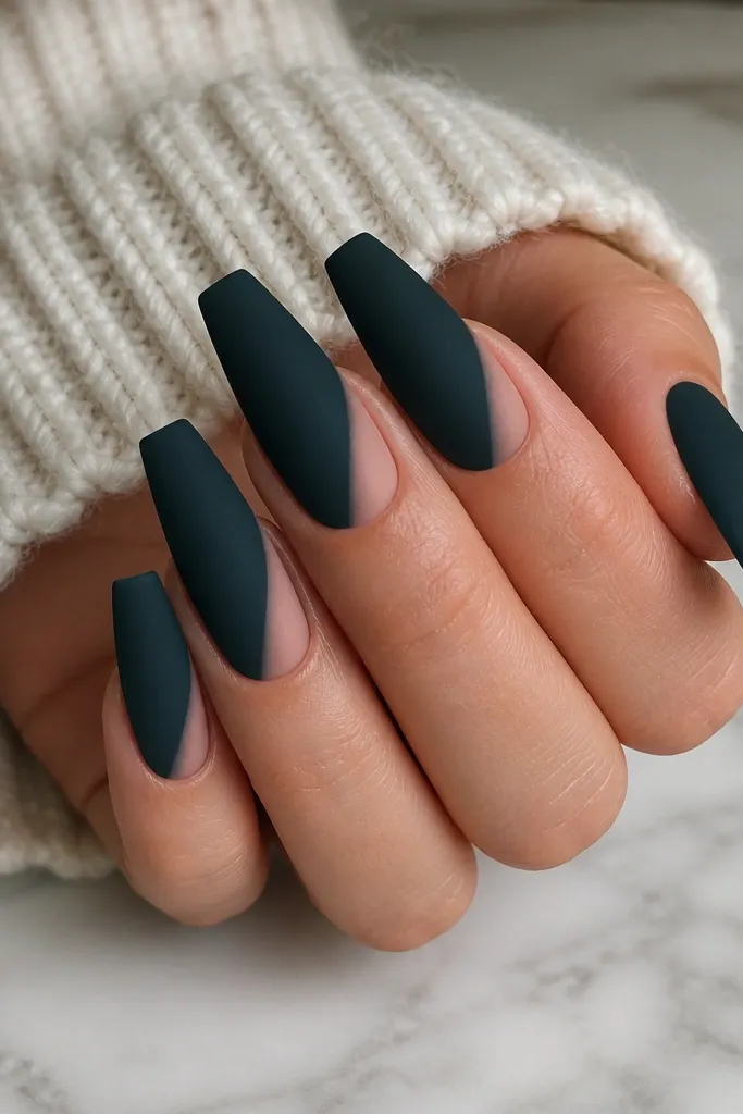 Coffin nails painted a blackened teal with a soft, velvety matte texture. Along one side of each nail, there is a narrow nude fade that looks like it's painted on a diagonal from mid-nail toward the tip. The matte finish looks plush and uniform.