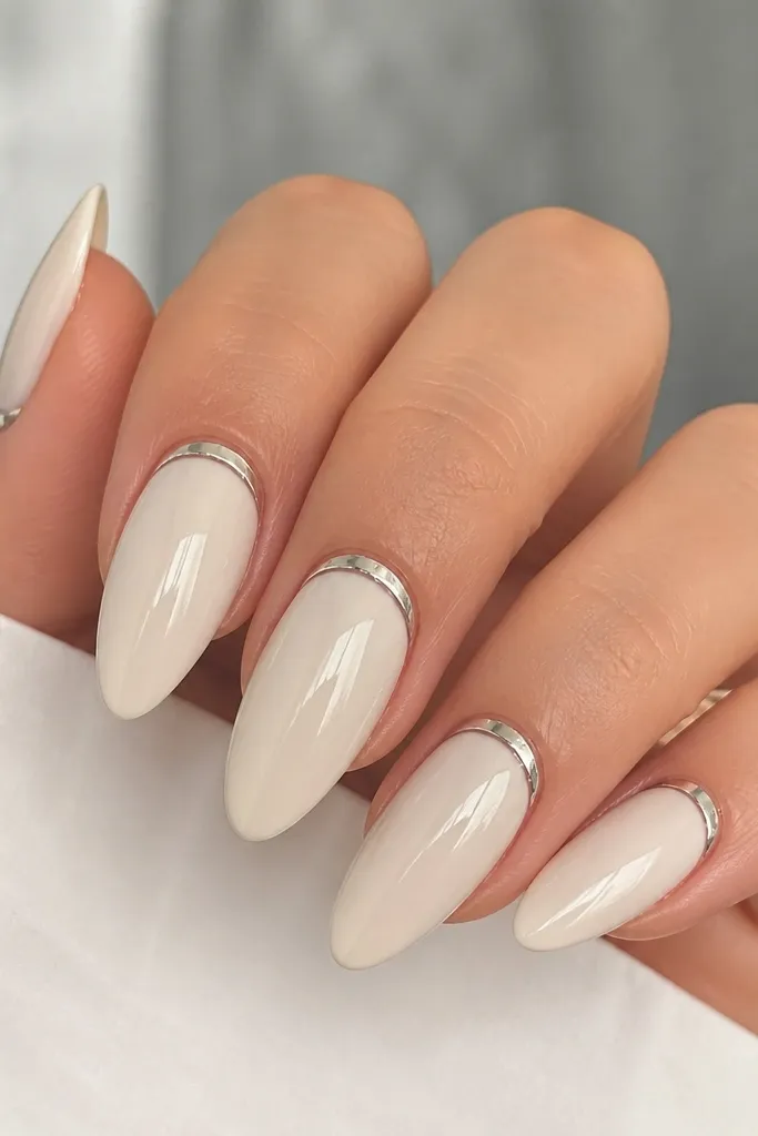 Long almond nails in a milky vanilla nude. A thin, reflective chrome stripe runs right along the cuticle line on each nail, with a mirror shine top coat.