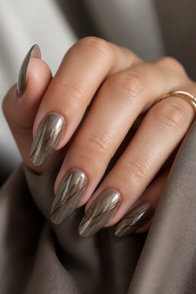 Long almond nails in smoky taupe chrome. Thin black micro-lines run diagonally across each nail like fine pen strokes.