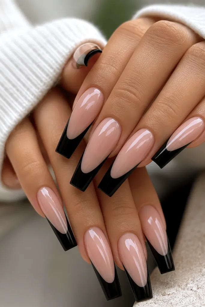 Long coffin nails with a nude pink base. The tips are painted a crisp, opaque black French line with a slightly squared edge, and the line is centered and symmetrical on each nail. High-gloss top coat reflects light like glass.