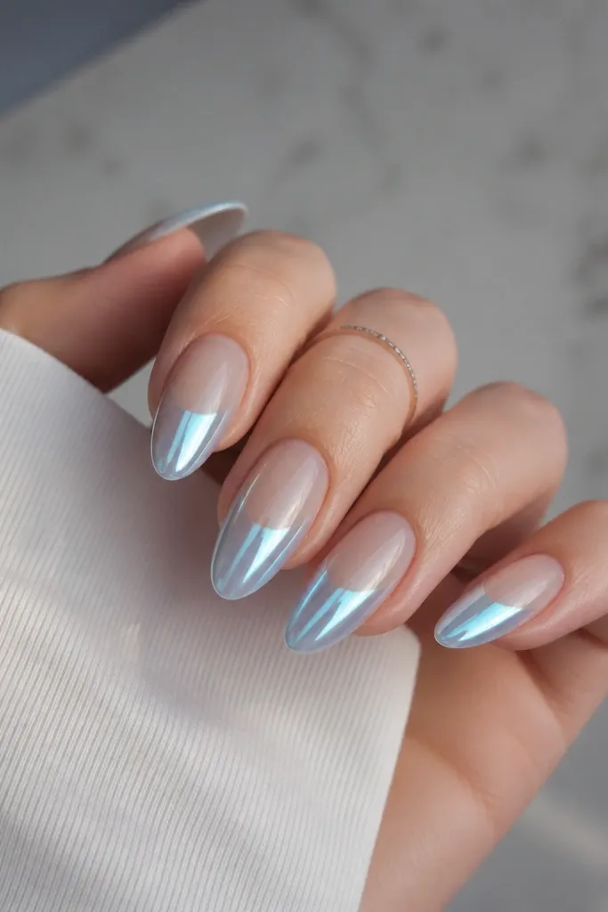 Long almond nails with a clear gel base. The tips fade into an icy blue chrome gradient, brightest near the free edge and softer toward the center. The surface is mirror smooth, catching cool light.