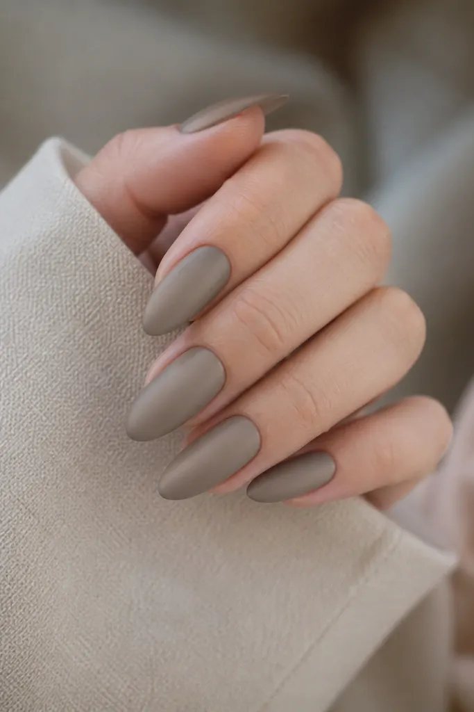 Long almond nails in a taupe greige color with a smooth soft-matte finish, no shine, evenly colored from cuticle to tip.