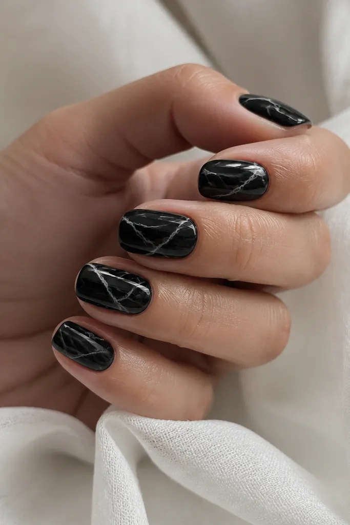 Short squoval nails with black base and white-gray marbling lines like onyx stone. The marbling looks thin and natural, with a glossy finish that makes it look glassy.