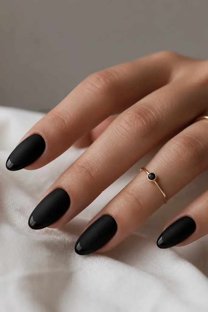 Almond nails with a matte black base. A very thin glossy black micro French line sits just at the tip edge, creating a subtle sheen outline.