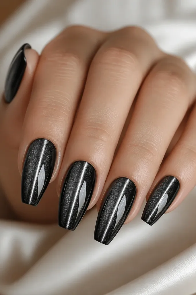 Coffin nails with black cat-eye gel. A thin straight silver highlight runs down the center like a rail, with a glossy finish and sharp symmetry.