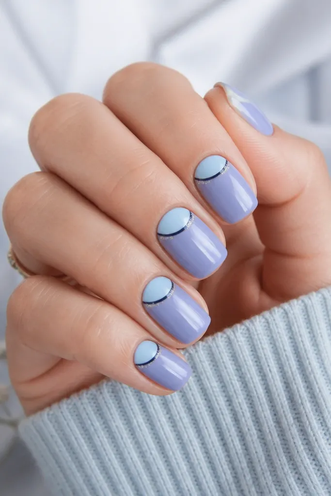 Short squoval nails painted icy periwinkle. Each nail has a clean half-moon at the cuticle in icy blue, while a thin navy line forms a curved border. The navy line has a tiny strip of fine micro-glitter only along the outer half of the border.