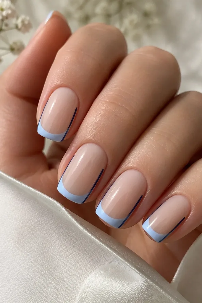 Medium squoval nails with a sheer nude base. The French tip is icy blue, applied as a clean smile line. Two super-thin navy lines run down the left and right side edges of the nail from near the tip toward mid-nail.