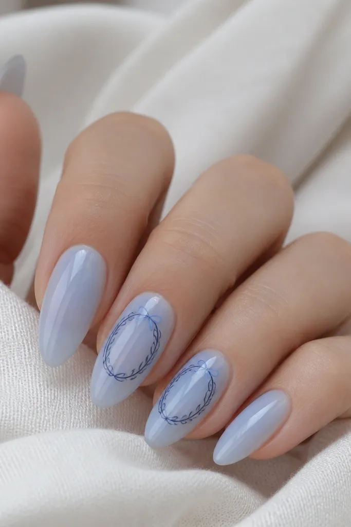 Almond nails in sheer icy blue. On two nails, there is a navy outline wreath centered near the tip, drawn with thin looping lines. A tiny icy-blue bow sits at the top of the wreath as a simple V shape.