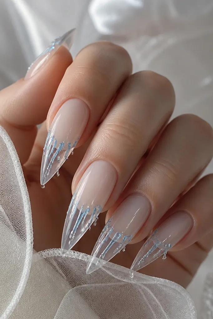 Clear almond extensions with an icy blue drip effect. The drips start near the tip edge and hang down in thin lines, with a frosty sparkle at the ends. The base is clear with a subtle milky tint.