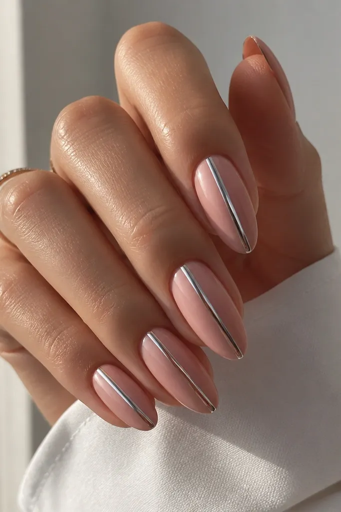 Almond nails with a rosy pink base. A single mirror chrome stripe runs straight down the center from cuticle to tip, with the rest of the nail staying matte-glossy pink and clean at the sides.