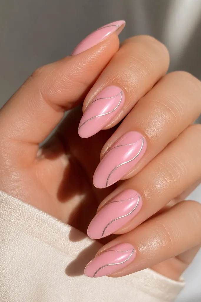 Candy pink almond nails with a glossy base. A thin chrome swirl starts near the cuticle and curves toward the side, leaving most of the nail pink and shiny.