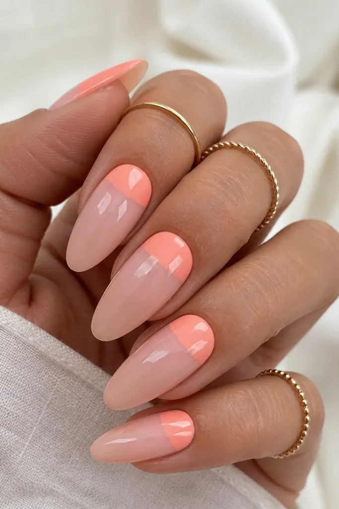 Long almond nails with a translucent nude-pink base. The top third of each nail is a peachy bubblegum color block, straight at the sides and slightly rounded at the cuticle of the block. Everything is glossy and clean.