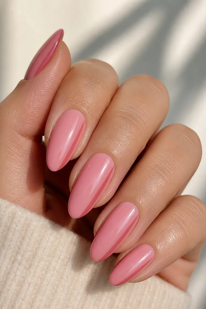 Almond nails painted in glossy rosy pink. On each nail, a single vertical side stripe runs down one edge from near the middle to the tip in a slightly deeper pink. The stripe is thin and straight, with crisp edges.