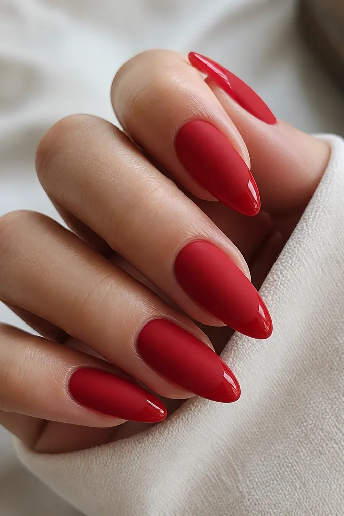 Almond nails painted matte red overall, with the very tip capped in glossy red or glossy clear. The contrast shows a clean line where matte meets shine.