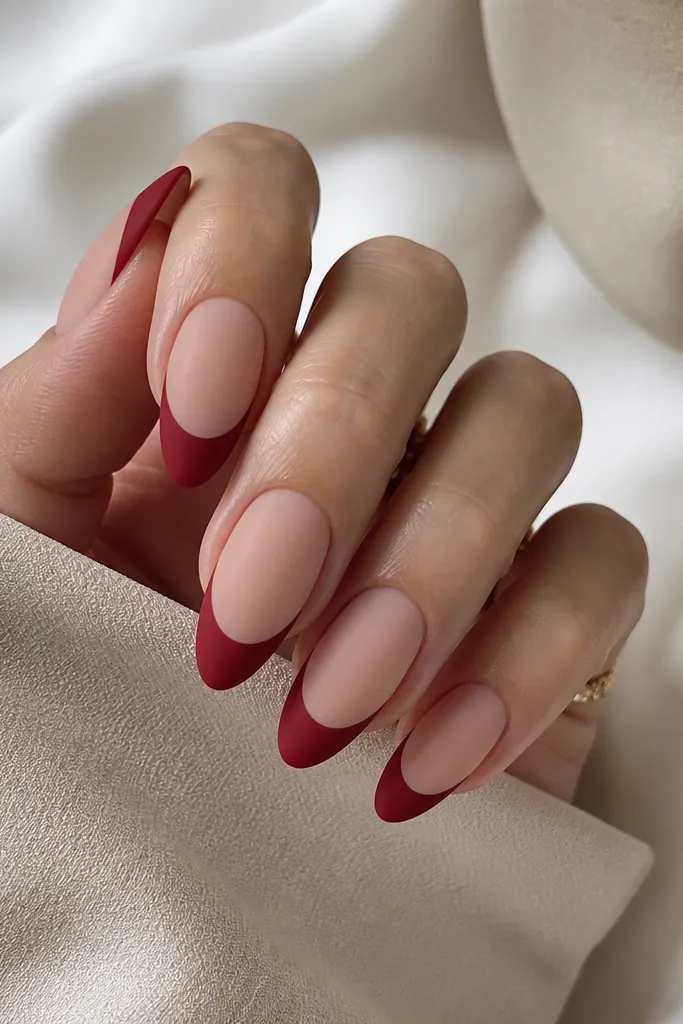 A full set of almond nails in nude beige. The French tips are matte brick red with a soft, slightly thicker smile line than micro French, and the matte finish looks velvety with no shine on the red.