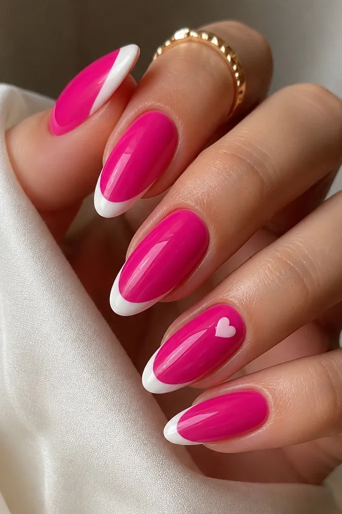 Hot pink almond press-on nails with white French tips and a small heart accent near the ring finger cuticle area. Glossy finish, heart is in white or pale pink, crisp outlines.