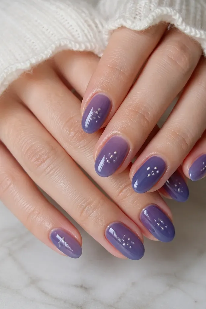 Short almond nails painted in a glossy blueberry jelly gel. On each nail, there are 2-4 tiny silver dots clustered near the center, like confetti. The base has a translucent, juicy look.