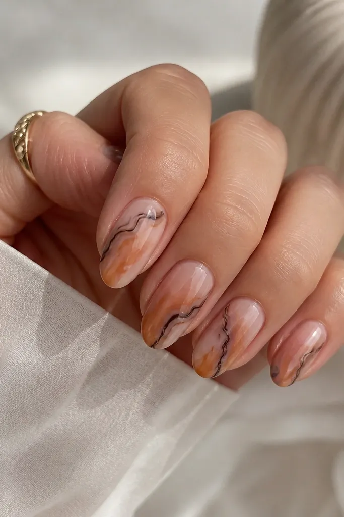 Short almond nails with a pink-beige base. Honey and caramel streaks look softer and slightly rosy, while darker cocoa lines form irregular borders. The pattern looks airy with visible base gaps, and the nails have a glossy finish.