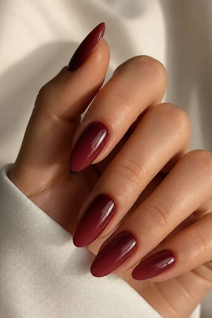 Almond nails with a smooth gradient: the base near the cuticle is a deeper burgundy, fading into a softer wine red toward the tip; glossy finish and no harsh lines.