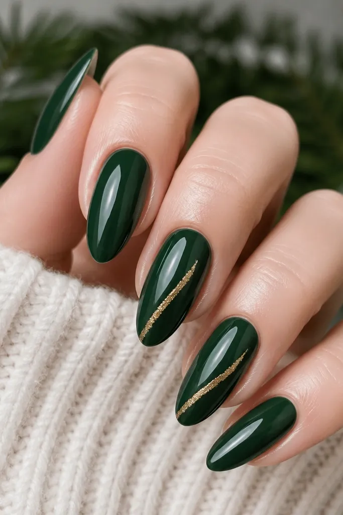 Long almond nails painted a deep pine green. Two nails have thin gold leaf lines that look like torn foil strips, placed diagonally from mid-nail toward the tip. Other nails are plain glossy green. The gold catches light and stays flat against the nail.
