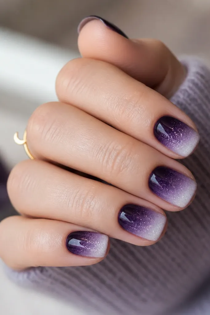 Short square nails with a deep midnight plum ombre fading into smoky lavender and then into sheer icy shimmer at the tips. Frost glitter is fine and evenly feathered.