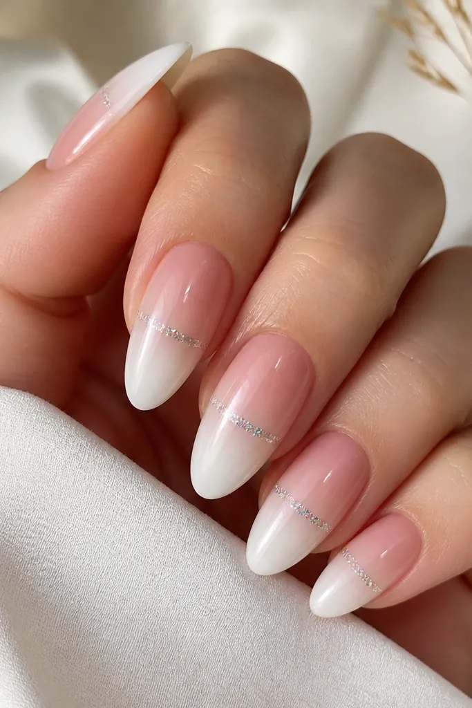 Almond nails with an icy pink ombre fading into sheer white tips. A single holo glitter line runs horizontally across the nail at the center fade.