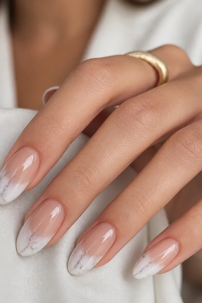 Nails with a nude base and a marble effect at the tips. The tips are white with soft grey veining, blending down from the free edge, with a glossy finish.